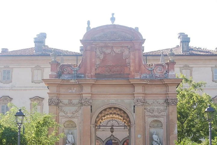 Das prunkvolle Barockportal der Villa Pallavicino mit Statuen und gemeißeltem Giebel, von Bäumen eingerahmt