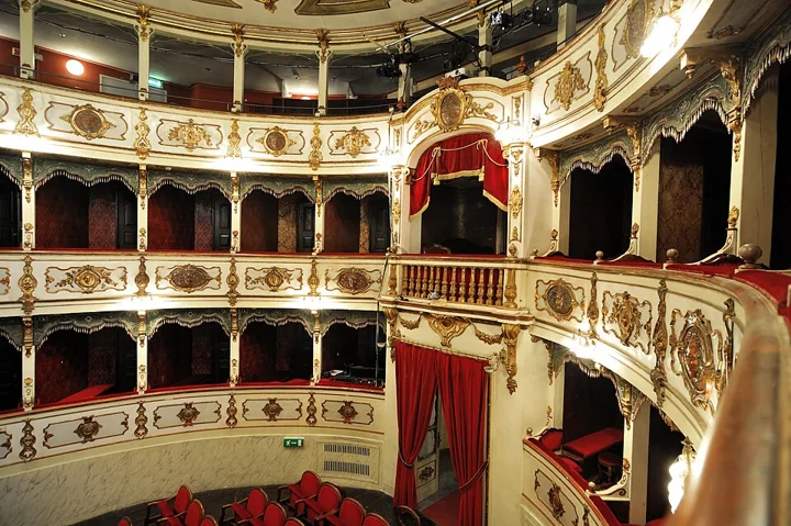 Der hufeisenförmige Saal des Teatro Verdi in Busseto mit Rängen vergoldeter Logen, roten Vorhängen und bemalter Decke